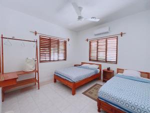 um quarto com 2 camas, uma secretária e janelas em Coconut Palm House - El Cuyo em El Cuyo