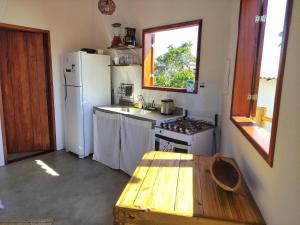 a kitchen with a white refrigerator and a wooden table at Acalanto do Sargi in Uruçuca