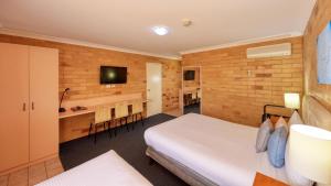 um quarto de hotel com uma cama e uma sala de jantar em North Parkes Motel em Parkes