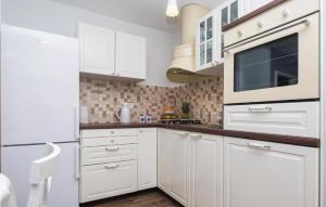 eine weiße Küche mit weißen Schränken und einer Mikrowelle in der Unterkunft Gorgeous Home In Hrvace With Wifi in Rumin