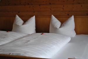 a bed with white sheets and pillows with two red buttons at Gasthof Panorama in Obsteig