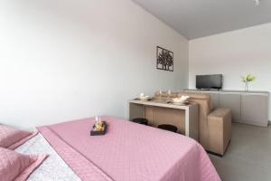 Un dormitorio con una cama rosa y un escritorio. en Galileia flat, en Santa Maria