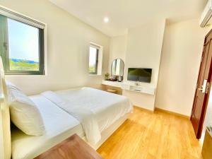 a white bedroom with a bed and a television at Khải Hoàn Hotel 2 in Bến Cát