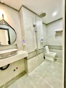 a bathroom with a sink and a toilet and a mirror at Khải Hoàn Hotel 2 in Bến Cát