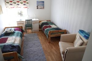 NorinkyläにあるOpintola Bed & Breakfastのベッド2台、デスク、ソファが備わる客室です。