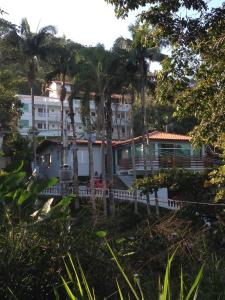 a building with palm trees in front of it at Recanto do Teimoso suites in Ubatuba