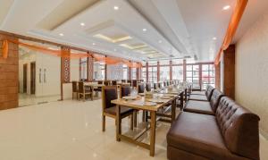 德拉敦Treebo G K Residency Near Dehradun Railway Station的有一张长桌子和椅子的餐厅