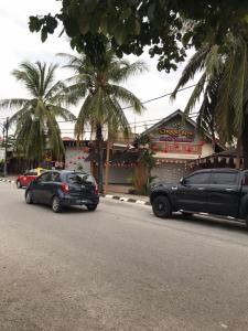 two cars parked on the side of a street at Lagenda Resthouse Langkawi in Pantai Cenang