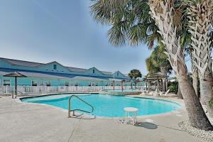 una piscina con una palma accanto a un edificio di Nemo Cay Stay a Corpus Christi