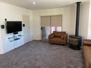 ein Wohnzimmer mit einer Couch, einem Fernseher und einem Sessel in der Unterkunft Coghill House in Yarrawonga