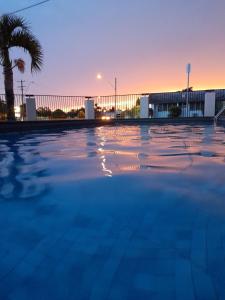 an empty swimming pool at sunset with a palm tree at Casa Nostra Motel Mackay in Mackay