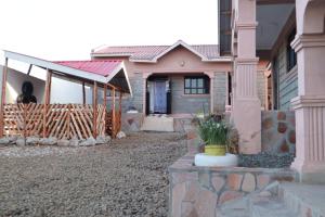 une maison avec une terrasse couverte et une personne debout en face de celle-ci dans l'établissement Lux Suites Mara Holiday Homes, à Narok