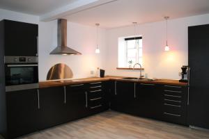 a kitchen with black cabinets and a sink at Søndervang, ferielejlighed in Svinninge