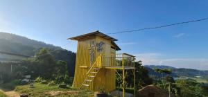 a yellow tree house with a ladder on a hill at BUKIT LIMAU REST HOUSE in Taiping