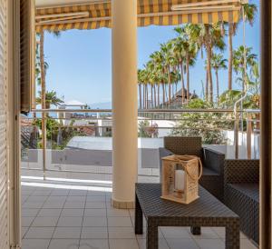 d'une terrasse avec une table, des chaises et des palmiers. dans l'établissement La Perla Apartment in Playa de Arena by Dream Homes Tenerife, à Puerto de Santiago