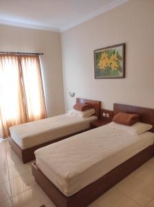 ein Schlafzimmer mit 2 Betten und einem Wandgemälde in der Unterkunft Adiputra Guesthouse Tata Bumi in Ngabean