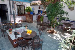 un patio al aire libre con mesas y sillas y fruta. en Pensión Aduar, en Marbella