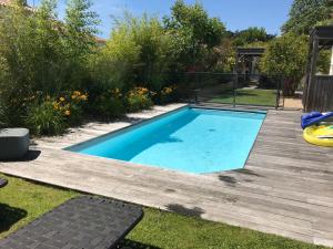 una piscina en un patio con terraza de madera en Villa 12 PERS - PISCINE, en Les Sables-dʼOlonne