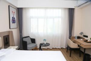 una camera d'albergo con letto, scrivania di 银座佳驿（潍坊寒亭高铁北站店） a Weifang