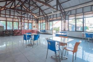 Hotel Markoni Pamanukan Mitra RedDoorz في Pamanukan-hilir: غرفة طعام مع طاولات وكراسي ونوافذ