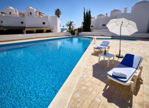 a swimming pool with two chairs and an umbrella at E&M Garden View Beach House VII in Porches