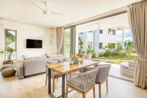 un soggiorno con tavolo, sedie e divano di Pineapple Beach Villas a Baie Lazare Mahé
