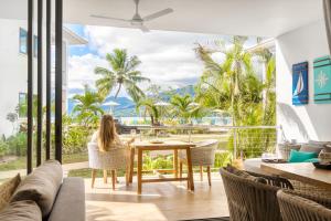 una mujer sentada en una mesa en una habitación con vistas al océano en Pineapple Beach Villas, en Baie Lazare Mahé