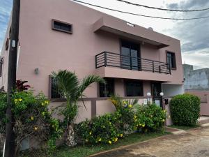a pink house with a balcony and some bushes at Villa Annjo in Pointe aux Piments