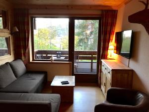 a living room with a couch and a large window at Megève - Appartement 2 chambres - Proche Centre et Pistes - Fibre - Parking in Megève