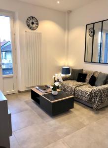 a living room with a couch and a clock on the wall at La maison d’Alice in Aix-les-Bains