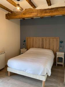 a bedroom with a bed with white sheets and wooden ceilings at Le Marquis De La Guintre in Courtils