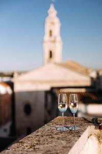 two wine glasses sitting on a ledge with a tower in the background at Santa Rosa Relais in Noci