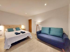 ein Schlafzimmer mit einem Bett und einer blauen Couch in der Unterkunft Villa Tabaiba en Lajares con Piscina in Lajares + 37 Fotos