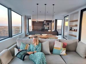 eine Frau, die auf einer Couch sitzt und ein Buch liest in der Unterkunft Villa Tabaiba en Lajares con Piscina in Lajares