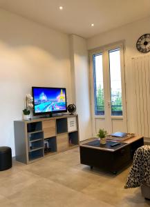 a living room with a flat screen tv on a wall at La maison d’Alice in Aix-les-Bains +6 photos