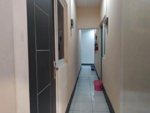 einen Flur mit schwarzer Tür und Fliesenboden in der Unterkunft RedDoorz At Kartini Residence Semarang in Semarang