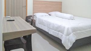 1 dormitorio con cama y mesa de madera en RedDoorz Syariah at Karema Area Mamuju, en Karema
