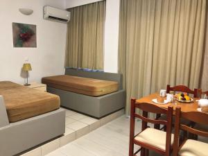 a room with a bed, table, chairs and a television at Caravel Hotel Apartments in Ixia