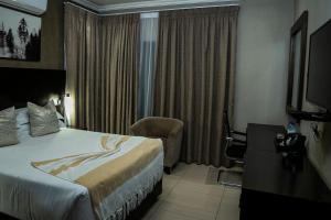 a hotel room with a bed and a chair at PeaconWood Boutique Villa in Palatswe