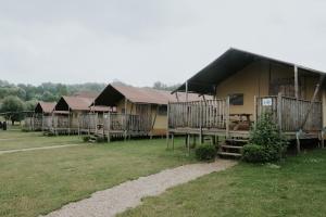 um grupo de alojamentos de turismo selvagem num campo com relva em Ijsmolenhoeve em Ronse