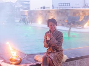 Una donna seduta accanto a una piscina con una candela di Hotel St. Florian a Frauenau