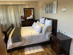 a bedroom with a bed with a dresser and a mirror at Thokomala Guest House in Germiston