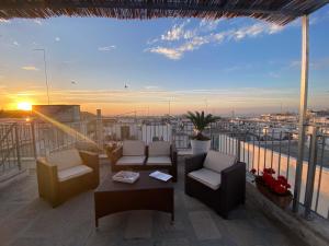 a balcony with chairs and a table and a sunset at 800s Home Luxury Rooms in Ostuni