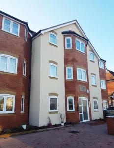 um grande edifício de apartamentos em tijolo com um branco em YBC Court, Aldershot em Aldershot