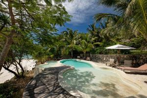 uma piscina com uma praia de areia e palmeiras em Qambani Luxury Resort em Michamvi