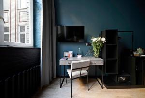 una scrivania in una stanza con un vaso di fiori di numa l Sketch Rooms & Apartments a Berlino