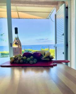a bottle of wine and a bunch of fruit on a table at Résidence Marine de Palumbare in LʼÎle-Rousse