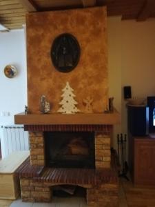 a fireplace with a clock and a christmas tree on it at Apartment Bolfenk in Pohorje +19 photos