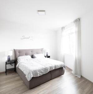 a white bedroom with a large bed and a window at Moderne 2 Zimmer Ferienwohnung mit Dachterrasse - 95qm in Bremerhaven