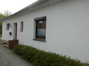 Una casa blanca con una ventana en el costado. en FeWo Ostseestrand, en Neustadt in Holstein
